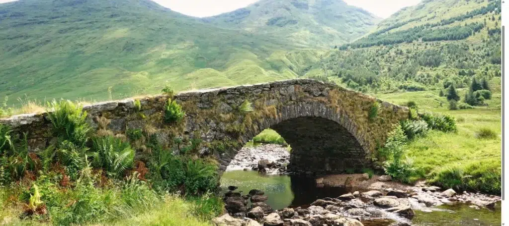 Old stone arched bridge over a river in a green Greek valley